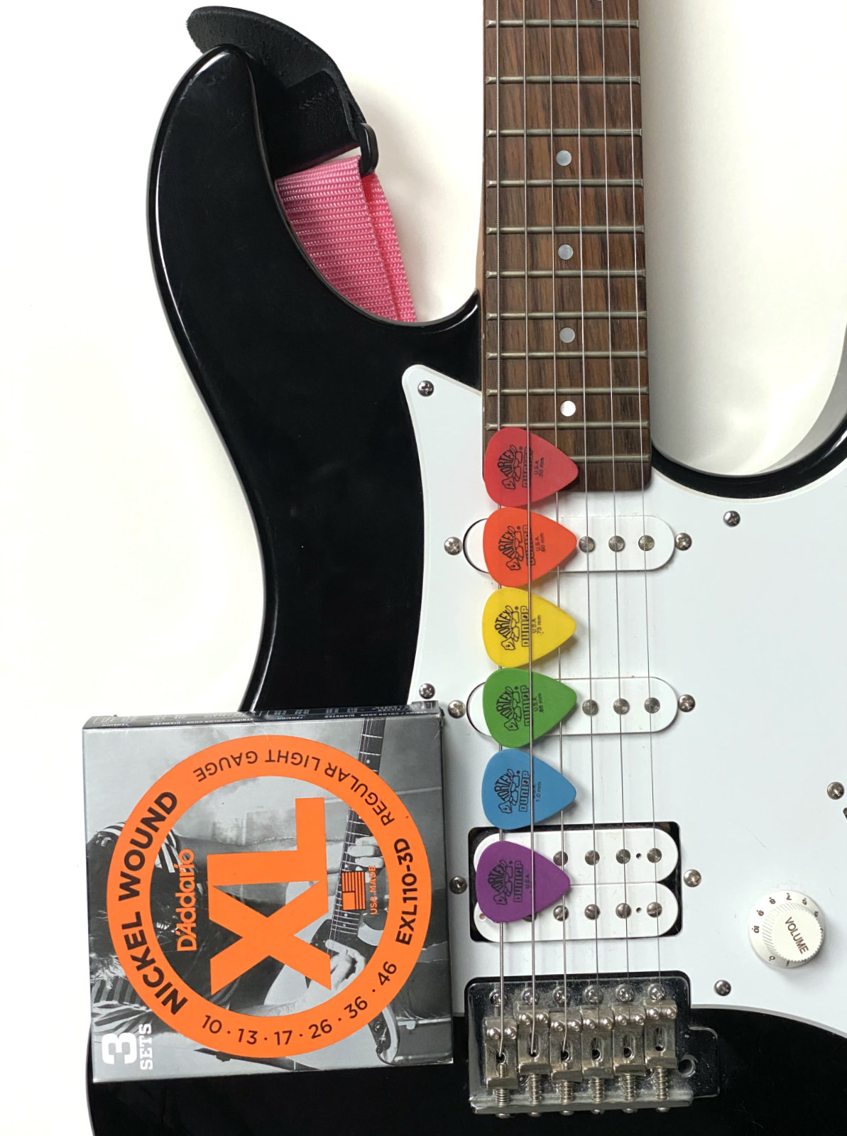 An electric guitar with some plectrums and a box of strings.